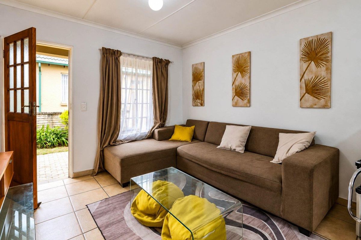 A living room featuring tiled flooring, coved ceilings, and direct access to an outdoor area through a timber-framed door.