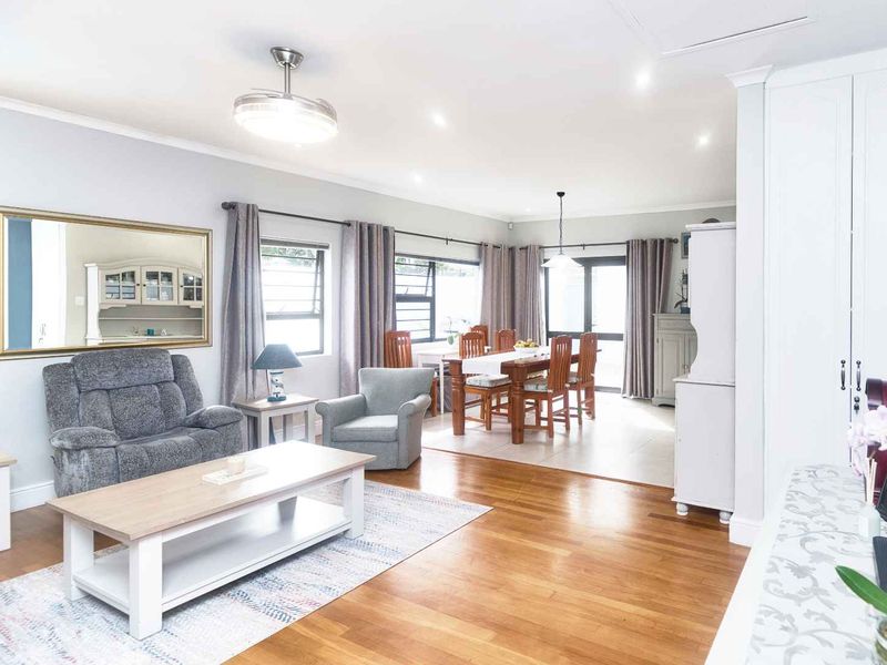 Spacious open-plan living and dining area featuring polished hardwood flooring, recessed lighting, and large windows providing ample natural light.