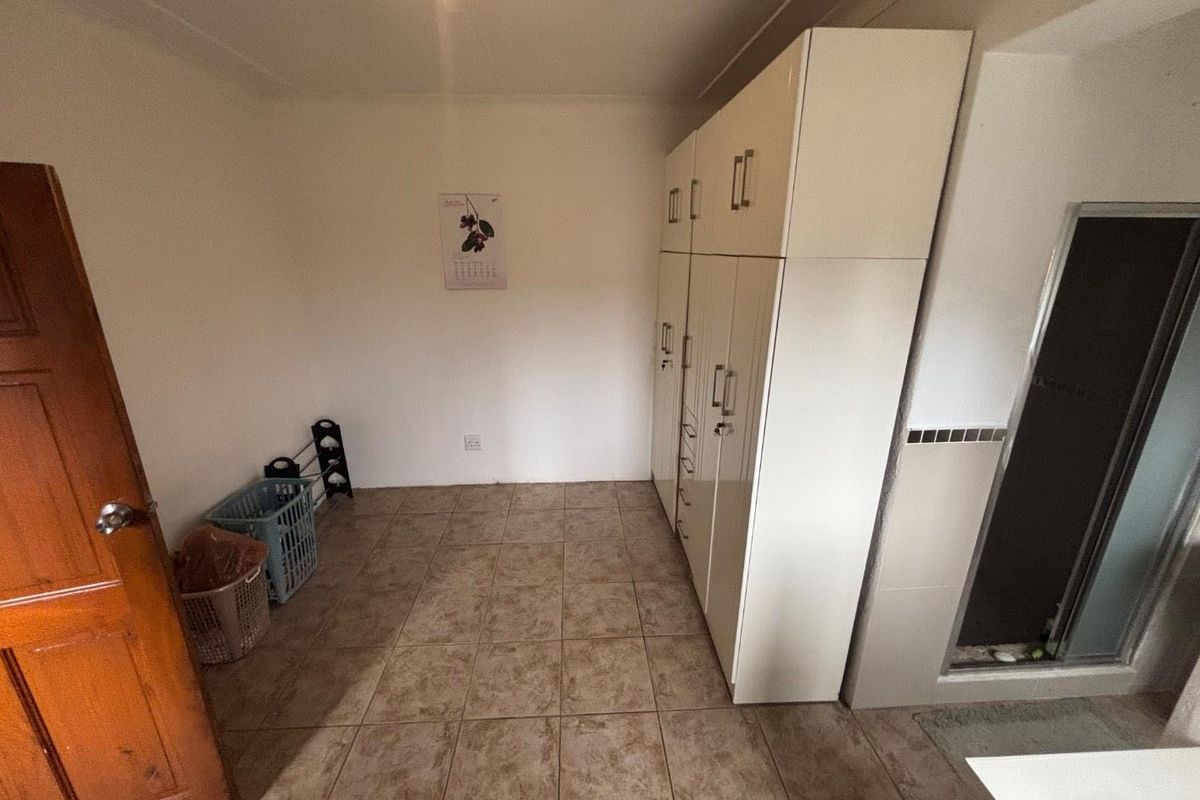 A functional bedroom featuring built-in floor-to-ceiling cabinetry, tiled flooring, and an adjacent en-suite bathroom entrance.