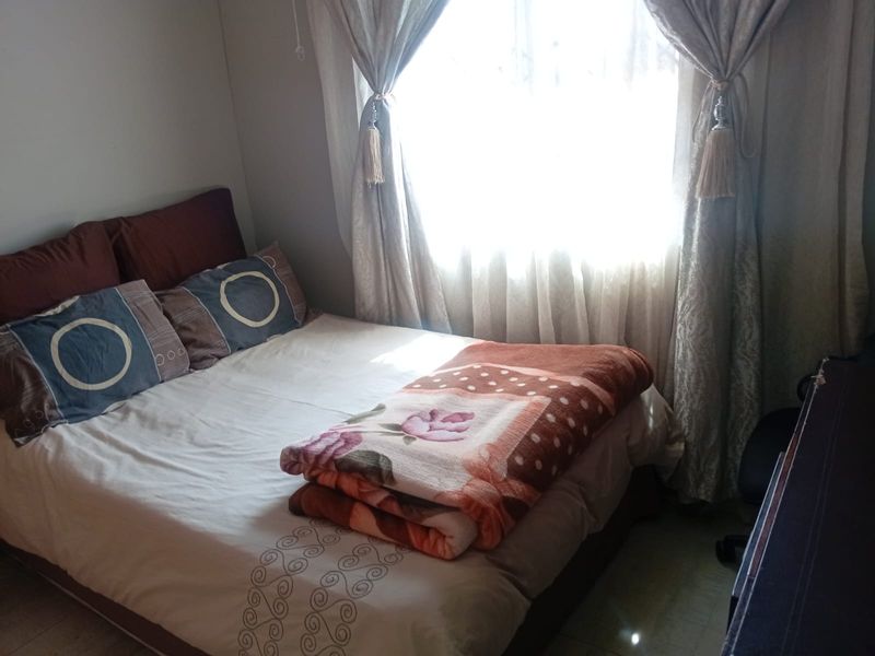 A standard bedroom featuring tiled flooring and natural light from a window.
