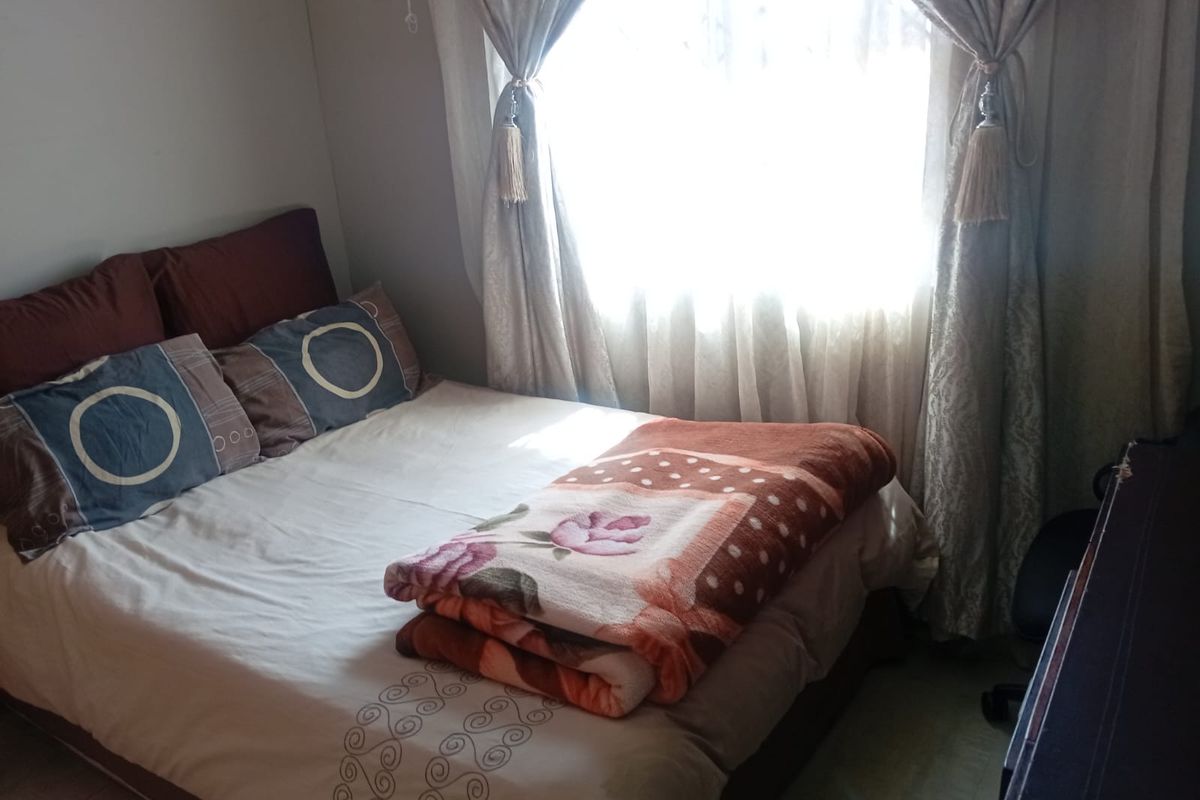 A standard bedroom featuring tiled flooring and natural light from a window.