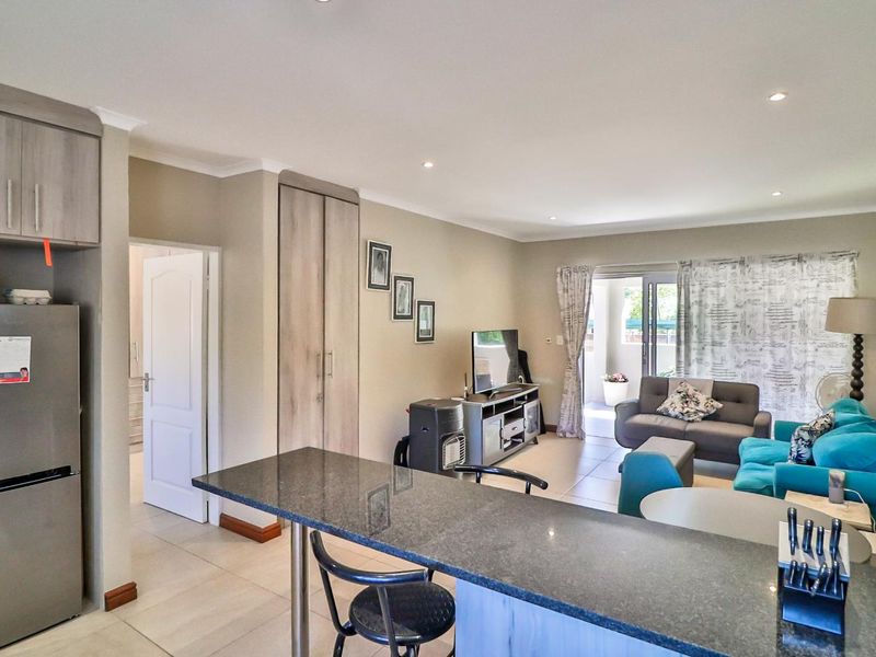 Open-plan living area featuring a granite breakfast bar, tiled flooring, and direct access to a patio through sliding glass doors.