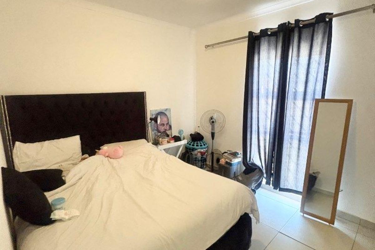 A bedroom featuring tiled flooring, a ceiling light fixture, and a sliding door with curtain rod access to an outdoor area.