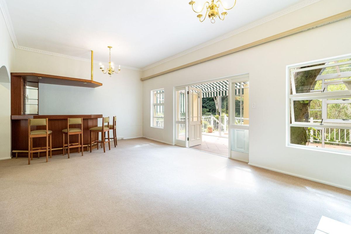 Spacious living area featuring a built-in wooden bar, carpeted flooring, and direct access to an outdoor patio through double doors.