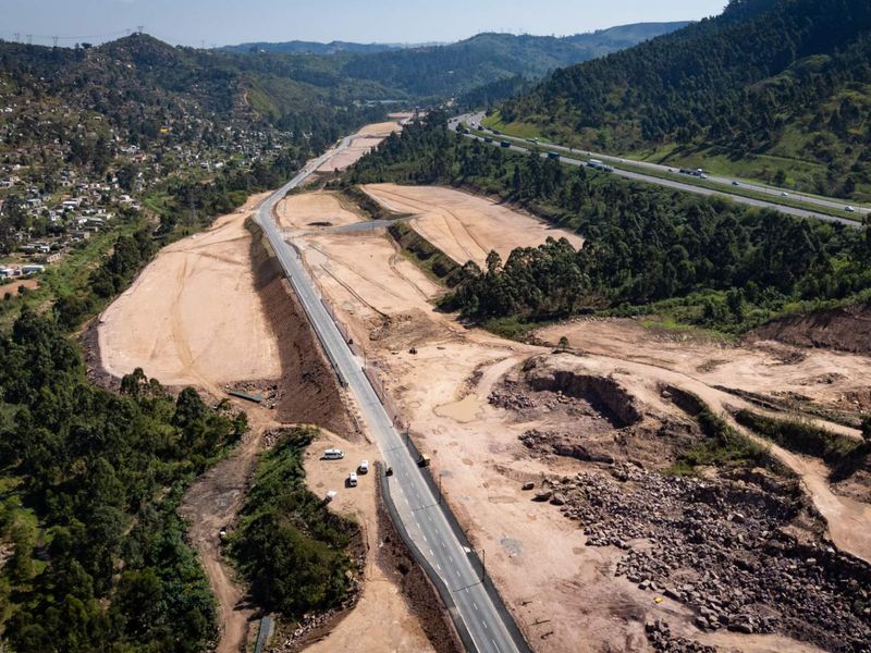 Aerial view of an industrial development site featuring extensive earthworks, cleared land, and an asphalt access road situated in a valley.