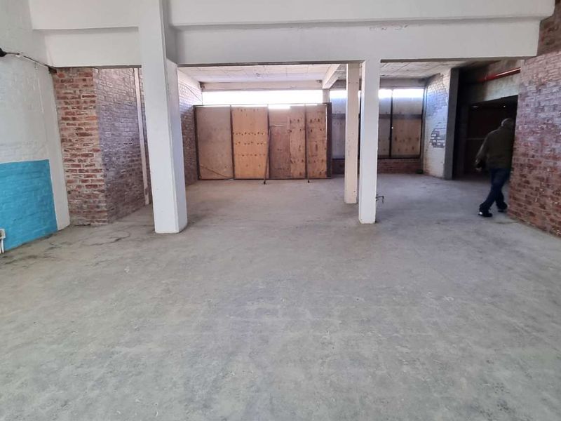 Spacious industrial open-plan area featuring exposed brick walls, concrete flooring, and structural support columns, offering a versatile blank canvas for renovation.