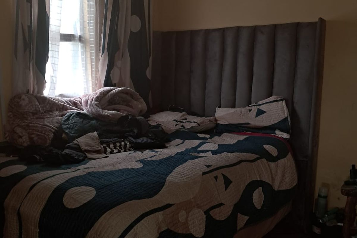 A bedroom featuring tiled flooring and a tongue and groove ceiling, currently showing signs of wear and requiring cosmetic updates.