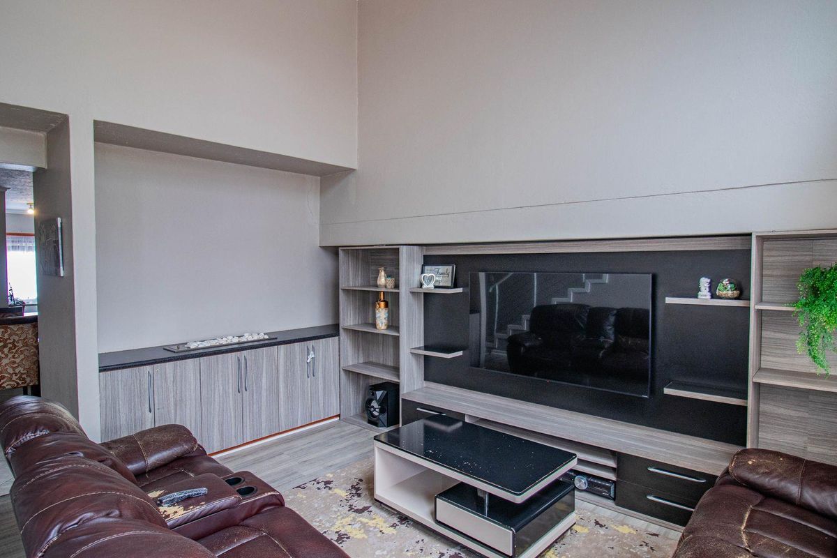 A spacious living room featuring a large built-in media wall unit with integrated shelving and cabinetry, providing ample storage and display space.