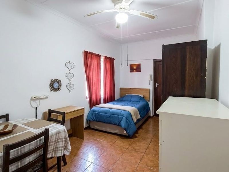 A compact bedroom featuring tiled flooring and a ceiling fan, offering a functional space with potential for cosmetic updates.