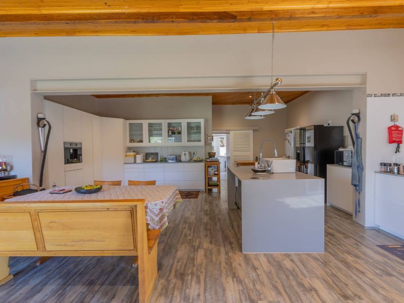 Spacious open-plan kitchen and dining area featuring a central island, modern cabinetry, and exposed timber ceiling beams, creating a bright and functional living space.