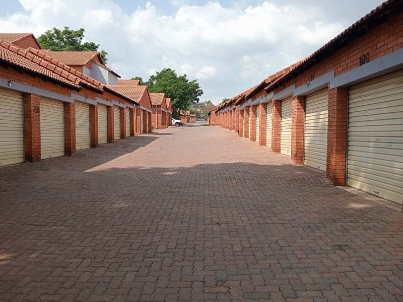 A row of brick-faced garages with tiled roofs and paved driveway access within an apartment complex.