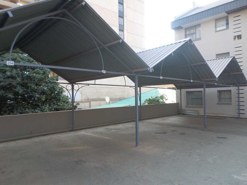 Covered parking area featuring a metal carport structure with designated numbered bays on a concrete surface.