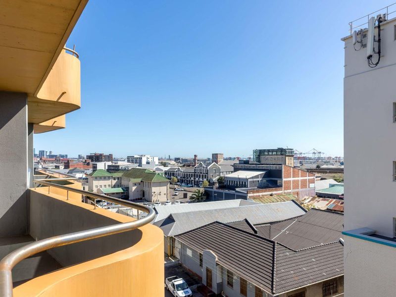 A spacious curved balcony offering an expansive urban city view, featuring a solid concrete structure and a metal safety railing.