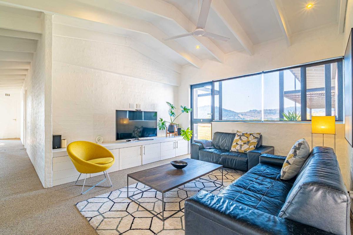 Bright living room featuring vaulted ceilings with exposed beams, large windows with scenic views, and built-in cabinetry.