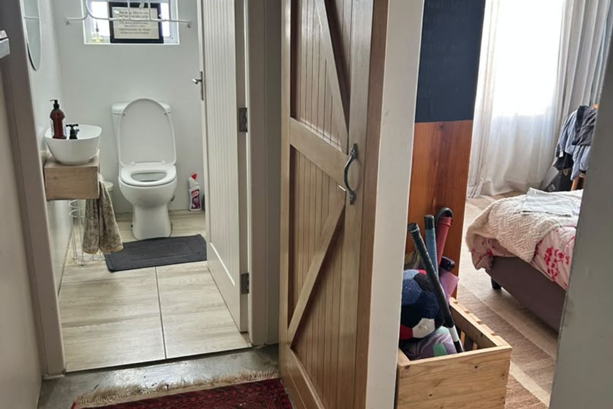 A compact bathroom featuring a modern vessel sink on a floating shelf, a toilet, and a sliding barn door entry.
