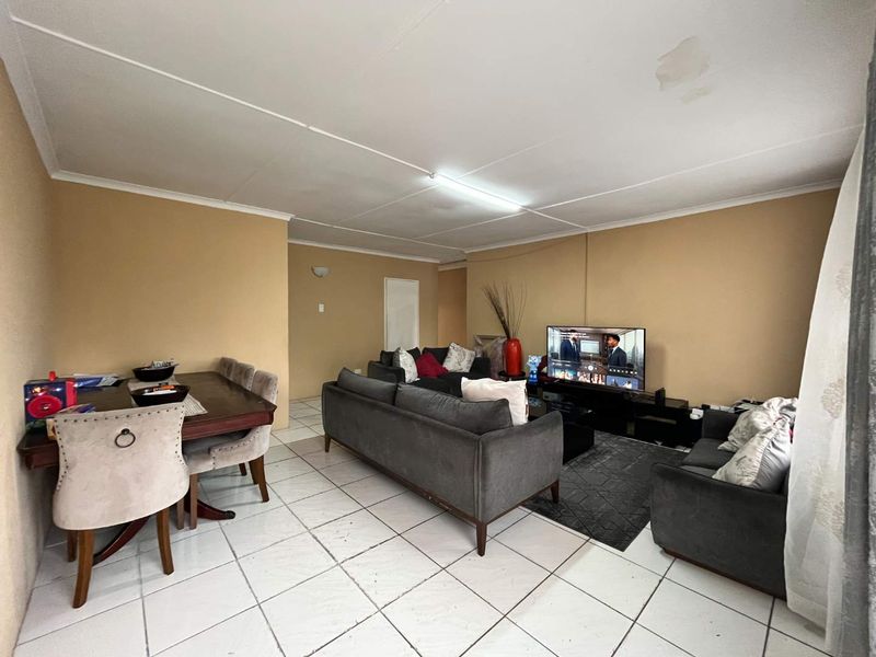 Open-plan living and dining area featuring tiled flooring and a ceiling with visible water damage and structural wear.
