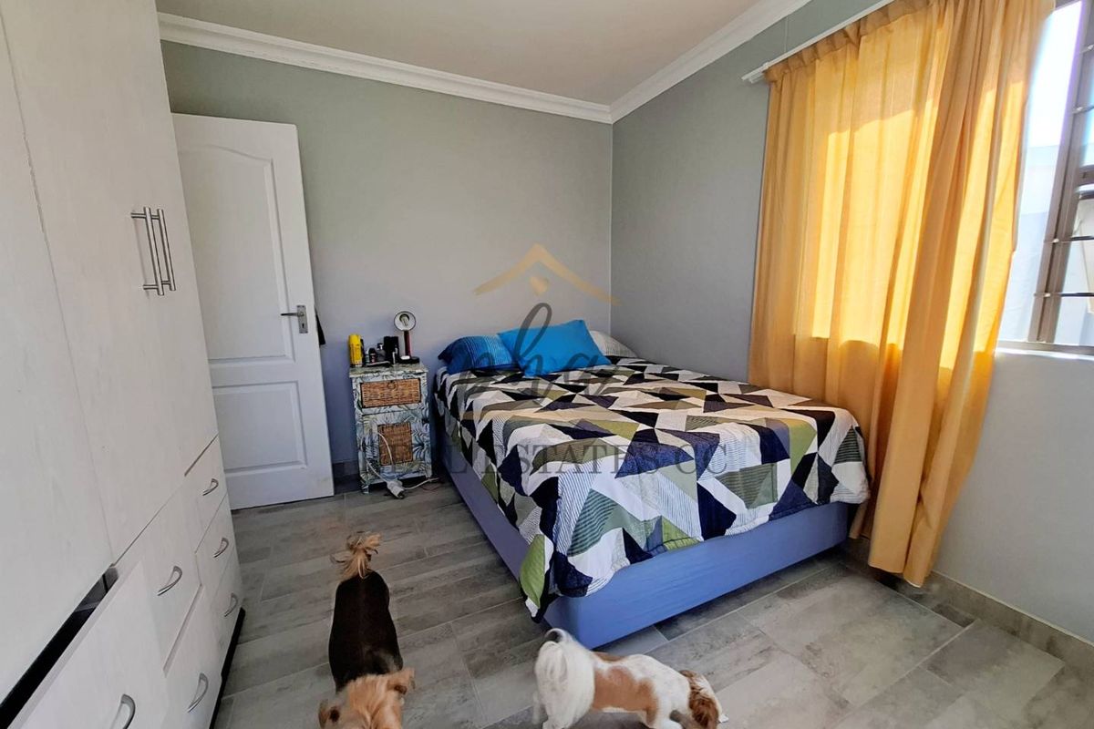 A functional bedroom featuring tiled flooring, built-in cabinetry, and a window with curtain treatments.