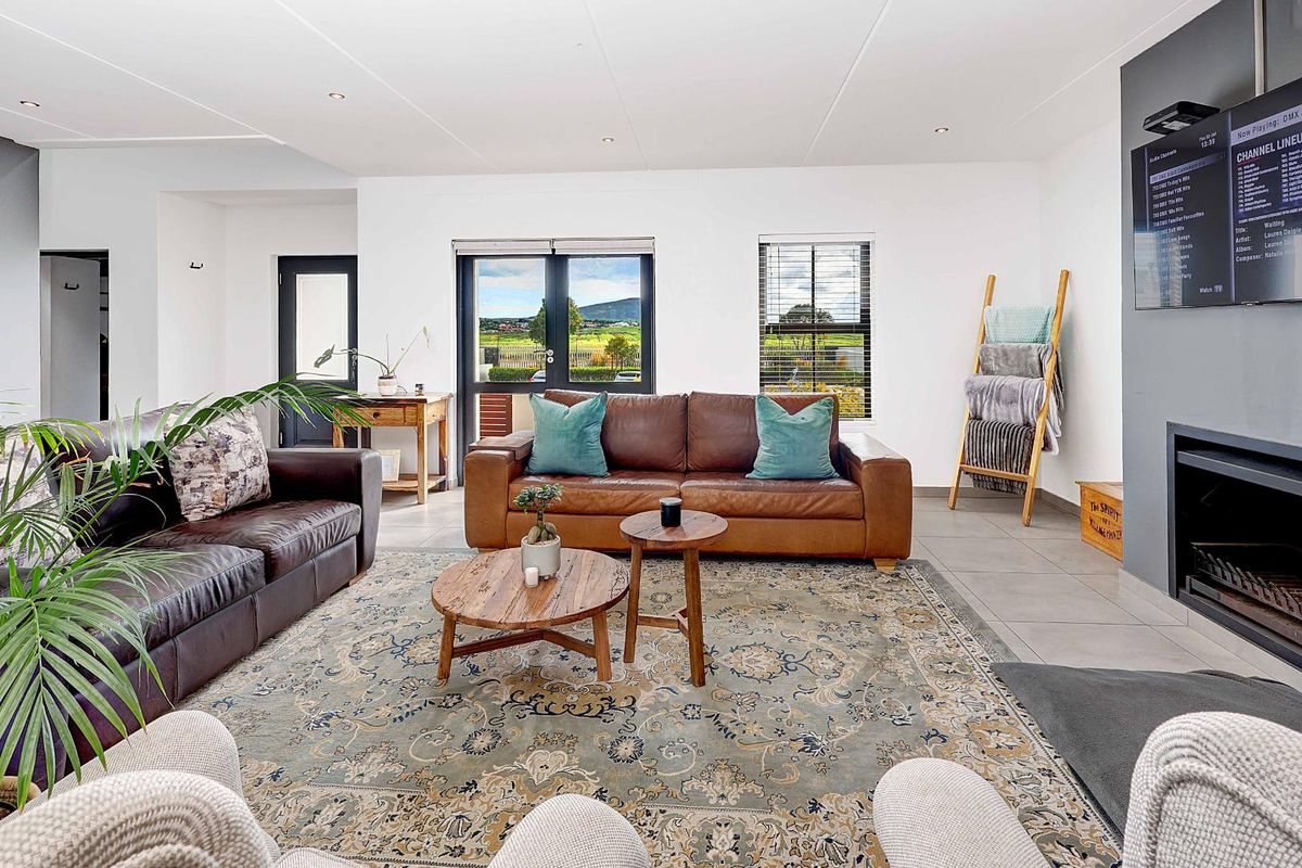 Spacious living room featuring large windows, tiled flooring, and a built-in fireplace, offering a bright and comfortable atmosphere with views of the surrounding landscape.