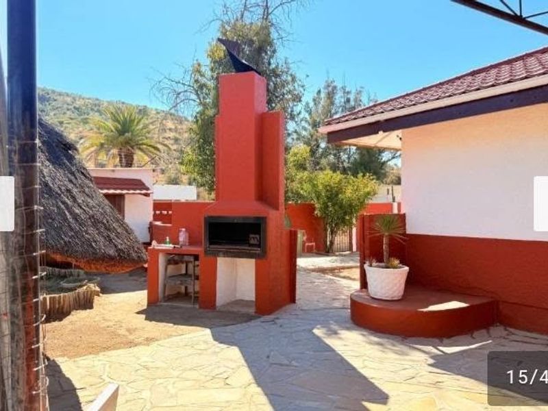 Outdoor patio area featuring a prominent built-in brick braai, stone paved flooring, and direct access to the rear garden space.