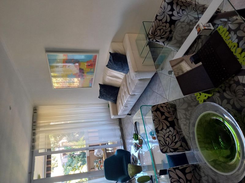 A bright living room featuring tiled flooring and large sliding glass doors that provide access to an outdoor balcony area.