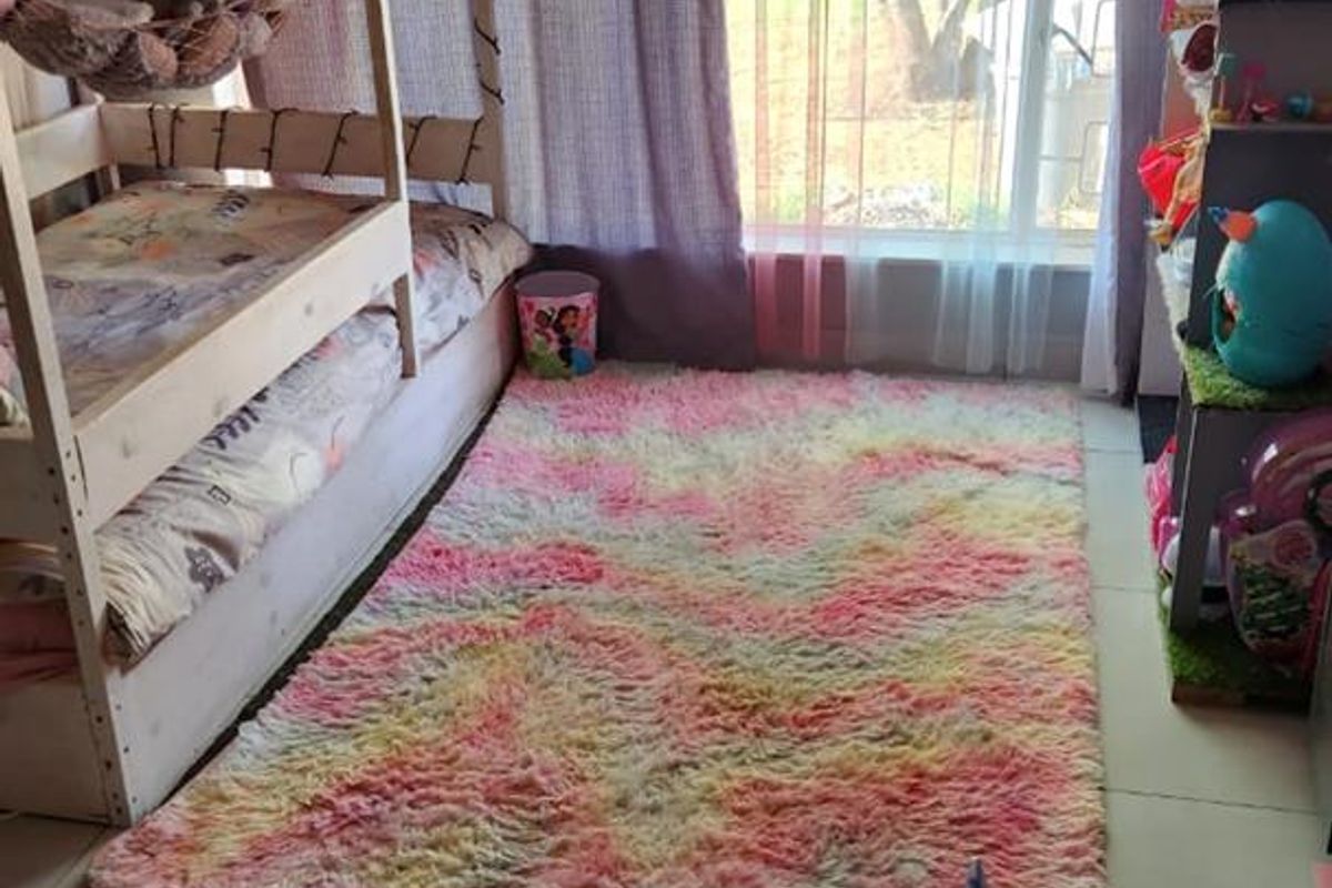A bedroom featuring large windows with curtains and tiled flooring.