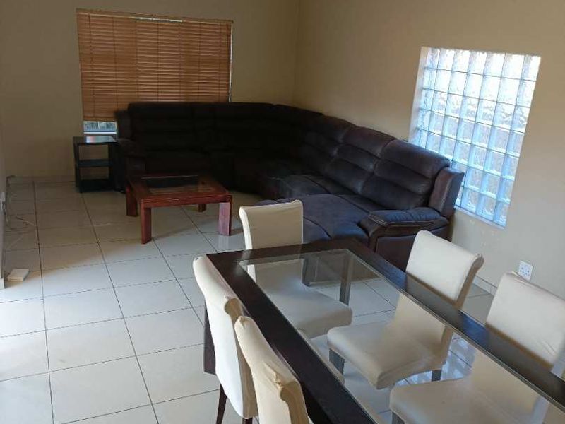 Open-plan living and dining area featuring tiled flooring, a glass block window, and venetian blinds, currently requiring ceiling light fixture repairs.