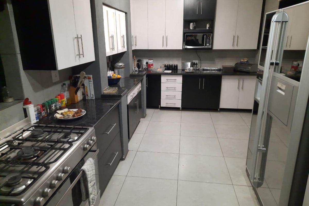 Modern kitchen featuring high-contrast cabinetry, granite countertops, tiled flooring, and a built-in gas stove with an integrated oven.