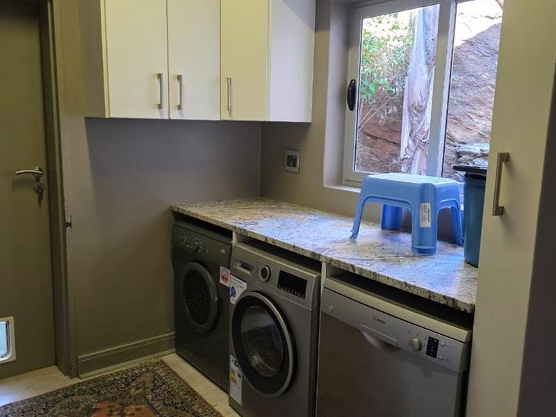 A functional laundry area featuring built-in cabinetry, granite countertops, and dedicated spaces for under-counter appliances.