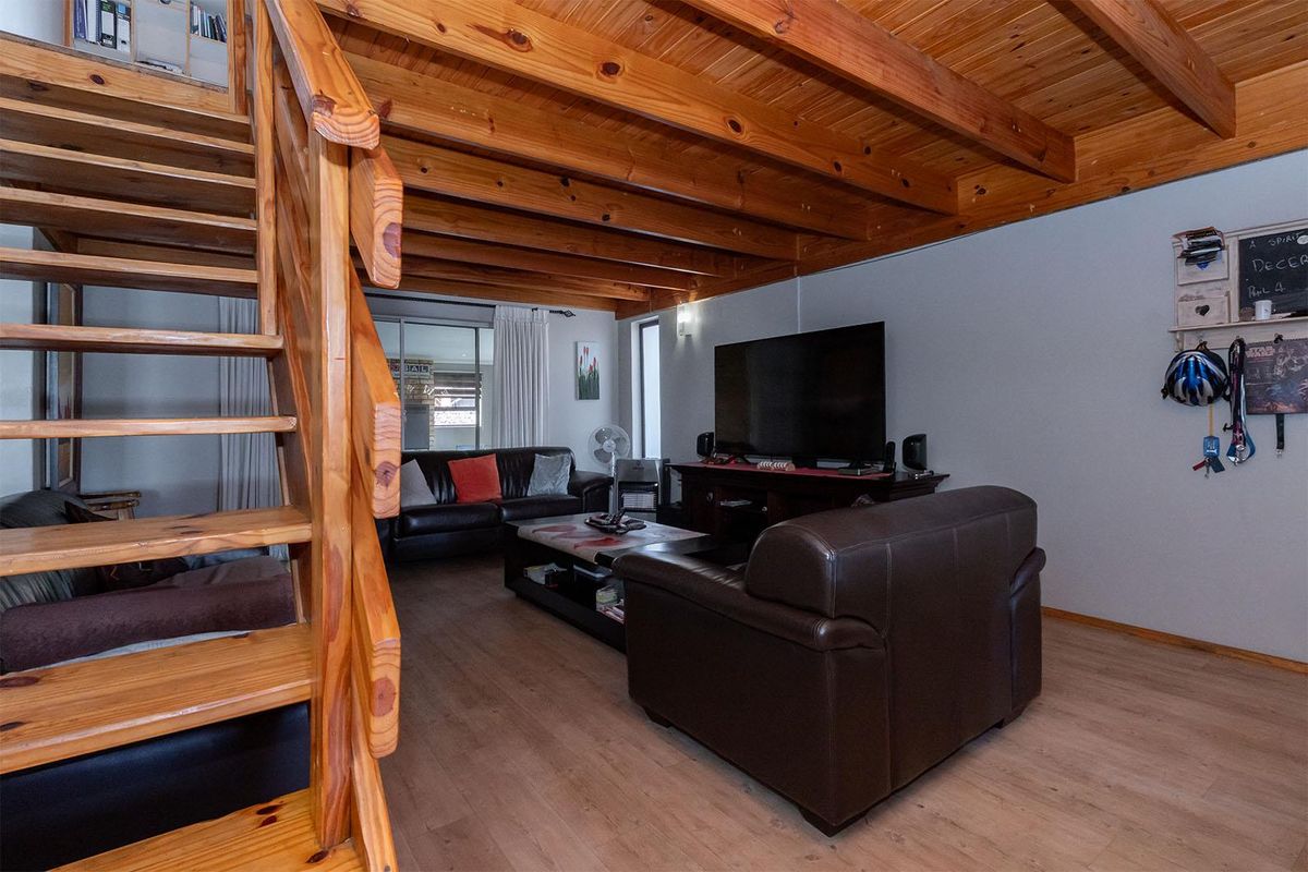 Open plan living area featuring exposed timber beam ceiling and a wooden staircase leading to an upper level.