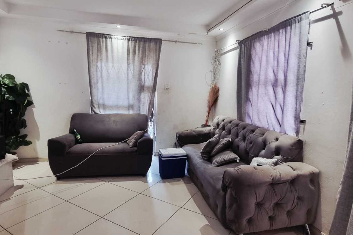 A living room featuring tiled flooring and recessed downlighting, offering a functional space ready for cosmetic updates.