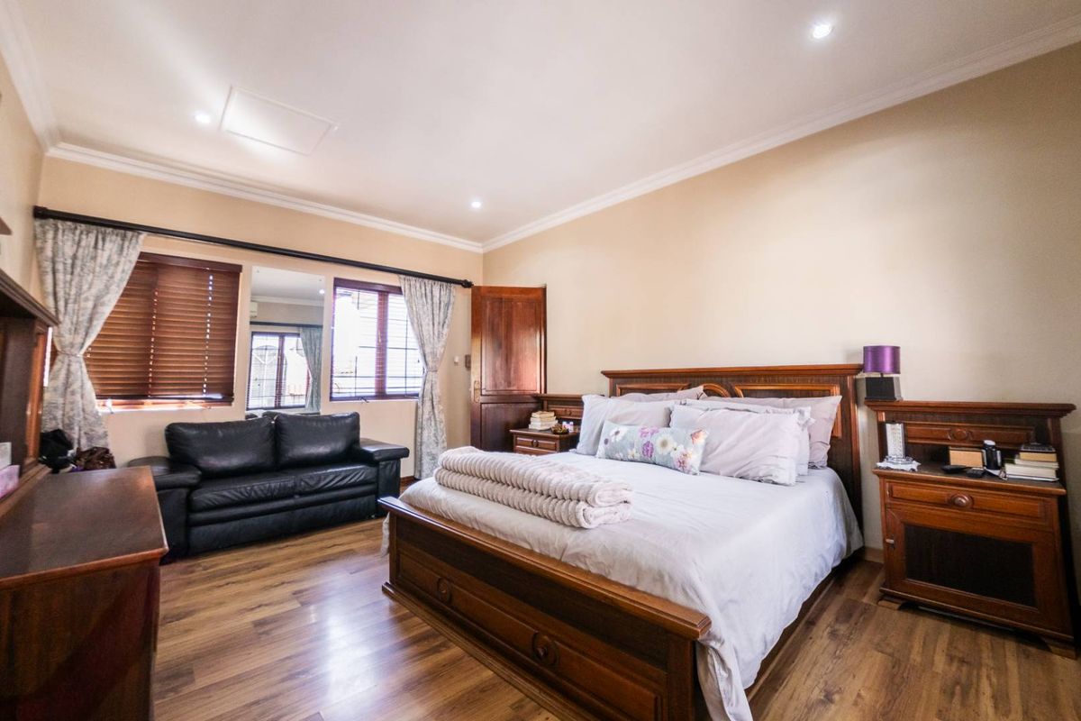 Spacious bedroom featuring wood-look flooring, recessed ceiling lighting, and wooden window blinds.