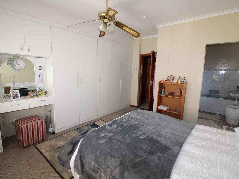 Bedroom featuring extensive built-in cupboards with an integrated vanity area, ceiling fan, and direct access to an en-suite bathroom.