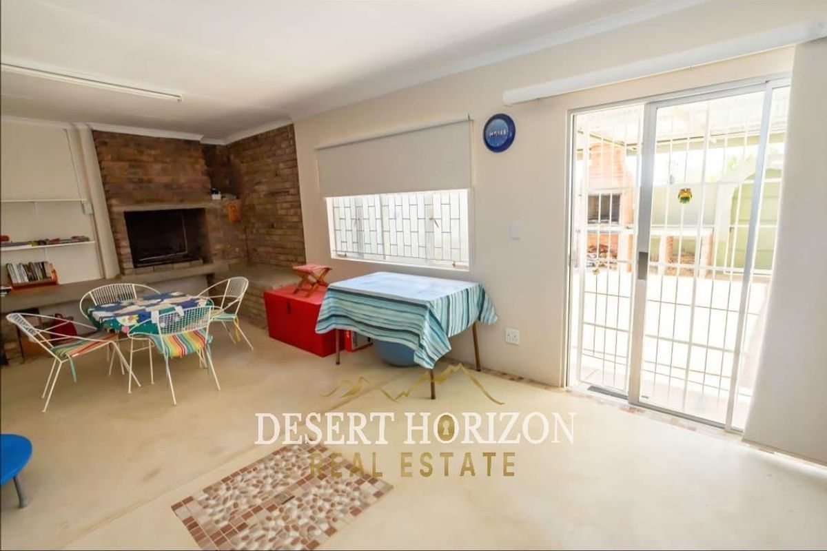 Spacious living area featuring a built-in brick fireplace and sliding glass doors providing direct access to the outdoor patio and braai area.