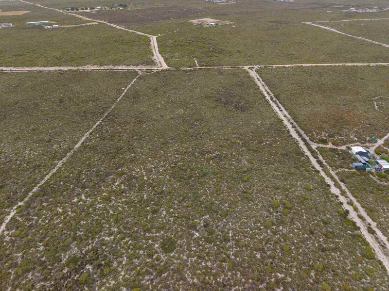 An aerial view of a large, undeveloped agricultural land parcel featuring native vegetation and dirt access roads.