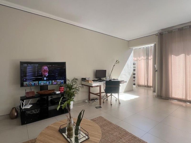 A bright and spacious living room featuring neutral tiled flooring, modern ceiling lighting, and large sliding glass doors providing ample natural light.