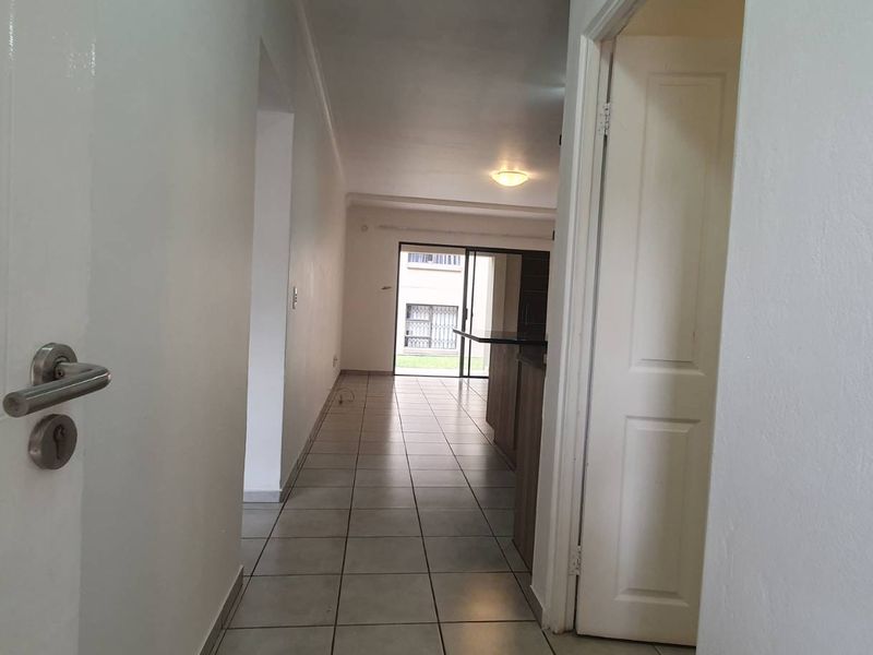 A view through a hallway leading into an open plan living area with tiled flooring and access to an outdoor space.
