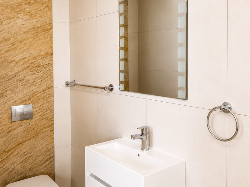Modern bathroom featuring a wall-mounted toilet, sleek vanity cabinet with basin, chrome fixtures, and neutral ceramic wall tiling.