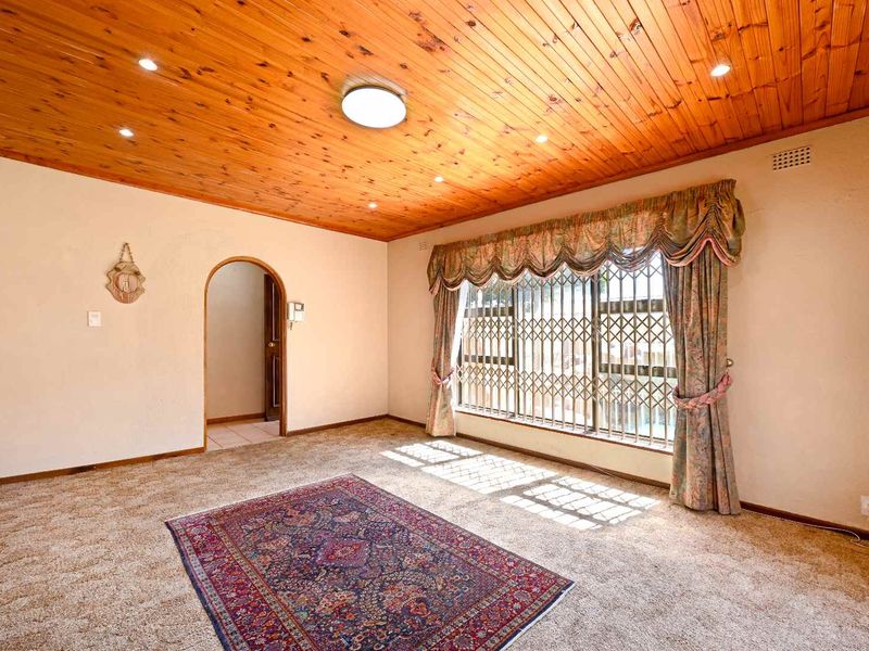 Spacious living room featuring a timber tongue and groove ceiling, recessed lighting, and a large window with security gate access.