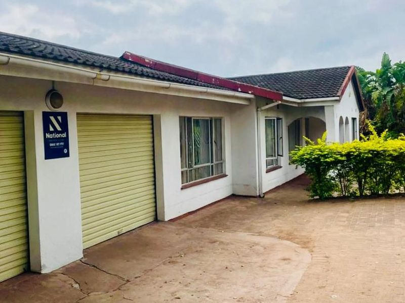 Front exterior view of the property featuring a paved driveway, roller garage doors, and tiled roof structure.