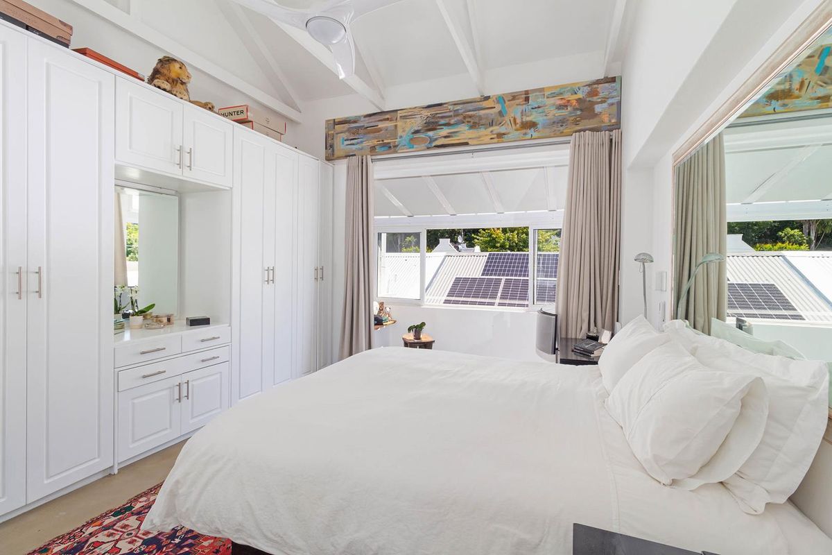 Bright bedroom featuring vaulted ceilings, a ceiling fan, and extensive built-in white cabinetry with integrated storage and mirror.
