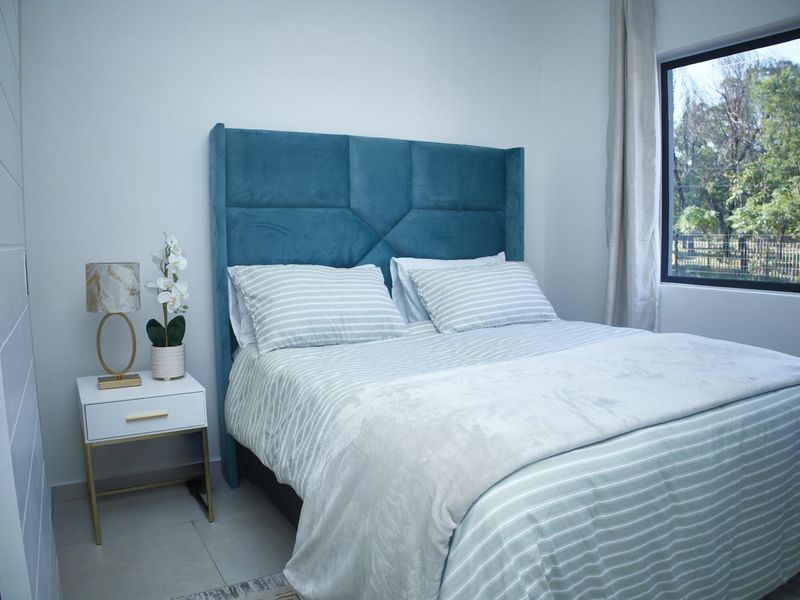 A well-lit bedroom featuring tiled flooring and a large window with natural views.