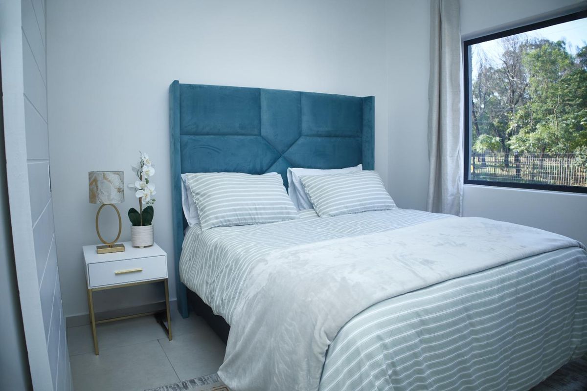 A well-lit bedroom featuring tiled flooring and a large window with natural views.