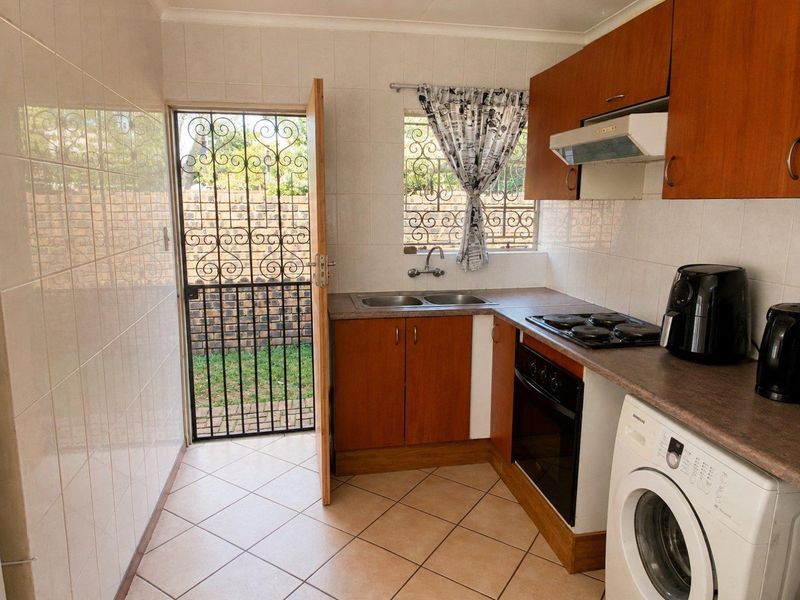 Functional kitchen featuring laminate countertops, built-in oven, electric hob, extractor fan, and direct access to the rear garden via a security gate.
