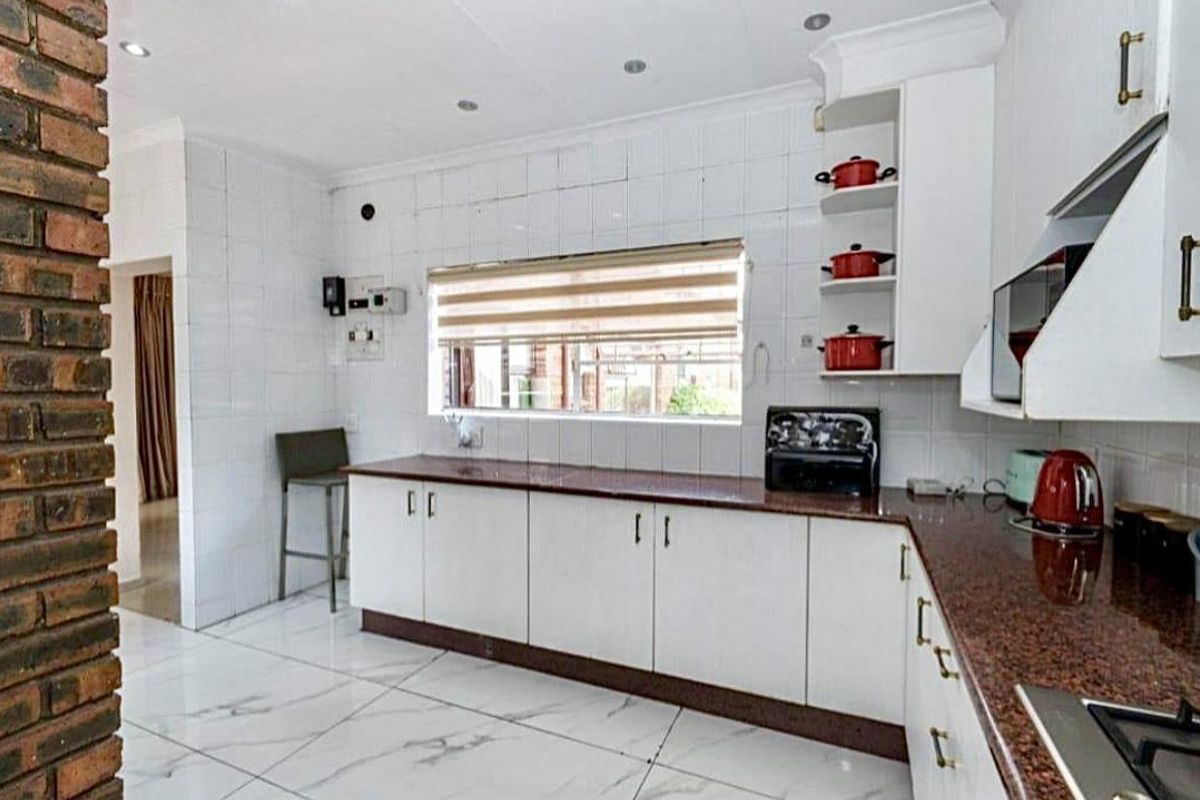 A functional kitchen featuring white cabinetry, granite countertops, tiled walls, and marble-look floor tiles with recessed ceiling lighting.