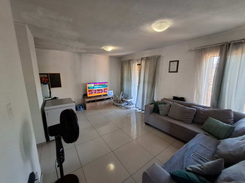 A living room featuring tiled flooring and ceiling lighting, showing visible signs of ceiling water staining requiring maintenance.