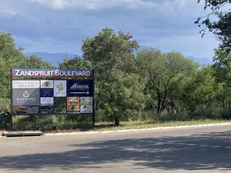 A street-level view of a commercial signage board located at the entrance of Zandspruit Boulevard, featuring various local business advertisements.