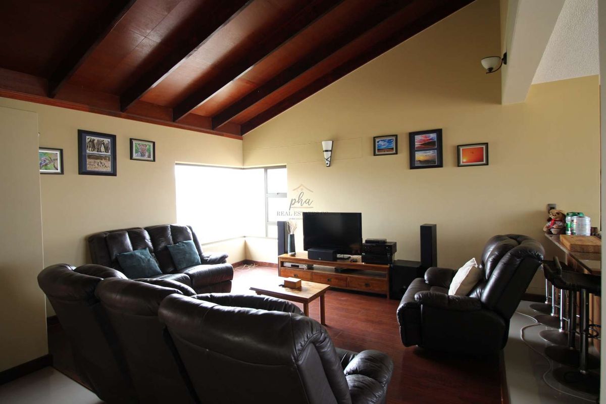 Spacious living area featuring high vaulted ceilings with exposed timber beams and warm-toned flooring, creating a comfortable and inviting atmosphere.