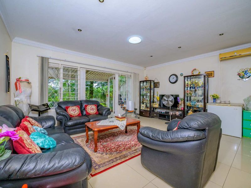 Spacious living room featuring tiled flooring, recessed lighting, decorative ceiling coving, and large sliding glass doors providing access to the outdoor patio area.