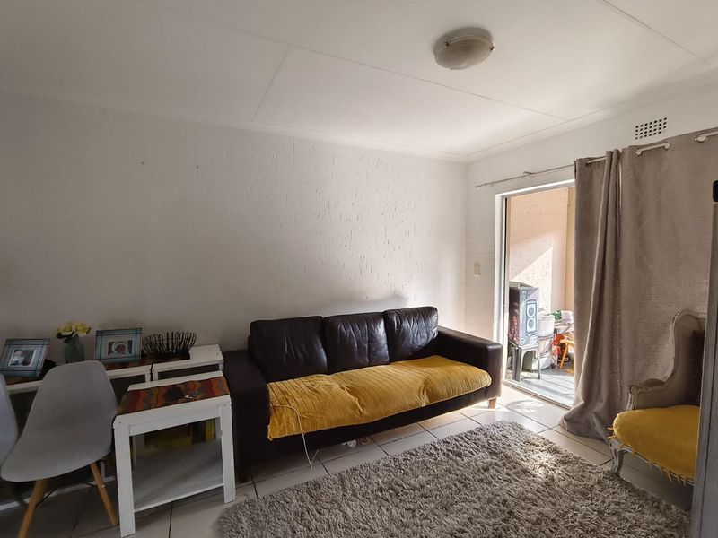 A living room featuring tiled flooring and a sliding glass door providing access to an outdoor area.