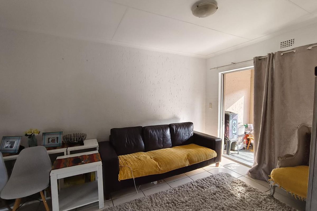 A living room featuring tiled flooring and a sliding glass door providing access to an outdoor area.